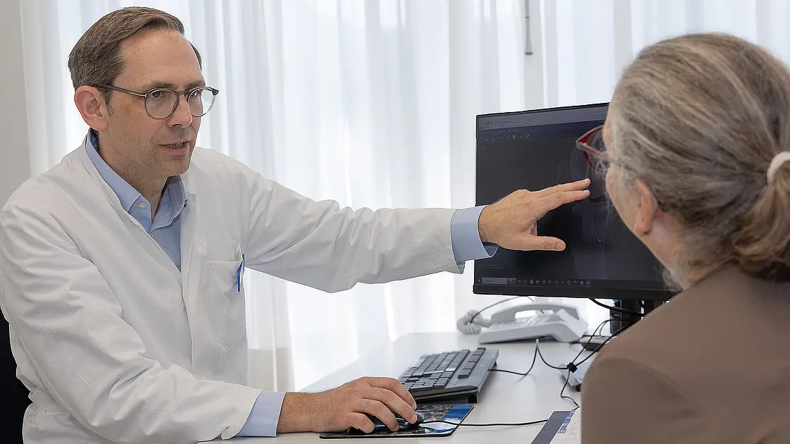 Ein Arzt zeigt einer Patientin an einem Bildschirm eine medizinische Aufnahme.