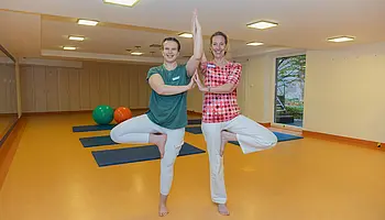 Zwei Therapeutinnen, die eine Yoga-Übung machen.