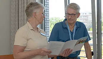 Eine Pflegefachkraft und ein Patient betrachten gemeinsam eine Informationsbroschüre.