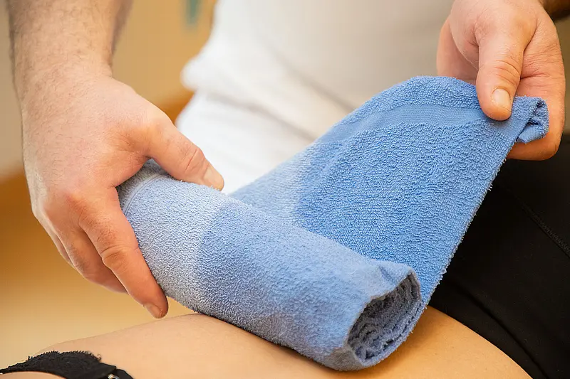 Ein heißes Handtuch wird vorsichtig auf den Rücken einer Patientin gelegt.