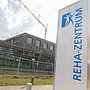 Außenansicht des Reha-Neubaus mit Baugerüst und Kran; im Vordergrund ein Schild mit der Aufschrift „Reha-Zentrum“, das Gelände ist noch abgesperrt